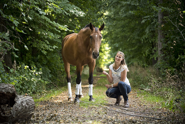 Pferdefotografie - Reiterin hockt neben Pferd